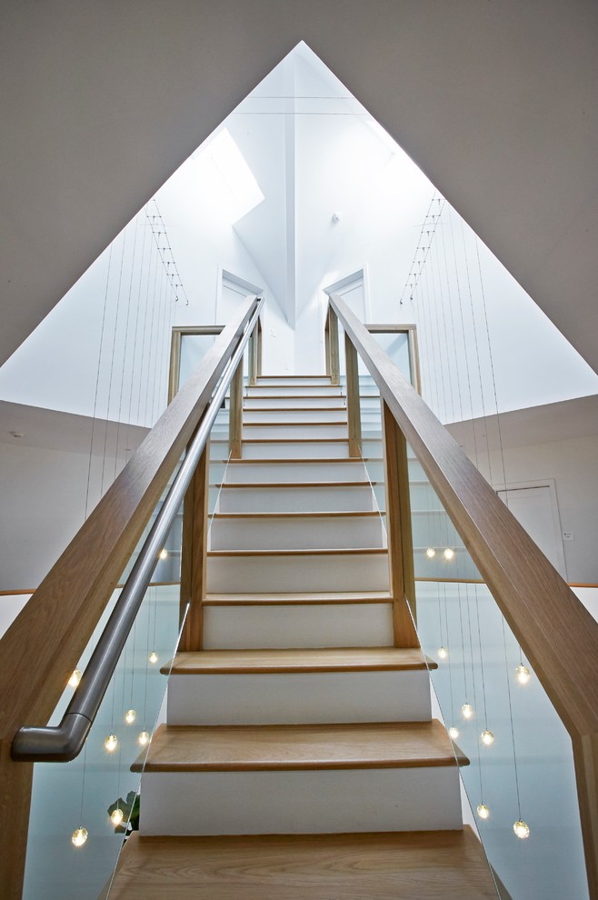 Diseño de escalera recta moderna grande con escalones de madera y contrahuellas de madera pintada