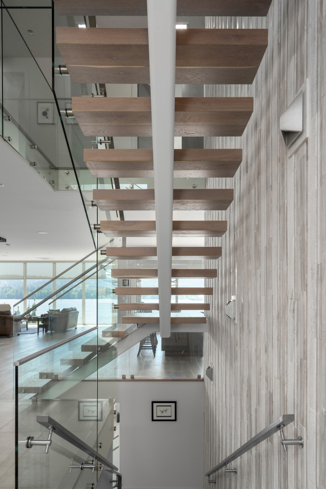 Inspiration for a large modern wood floating glass railing staircase in Vancouver with metal risers.