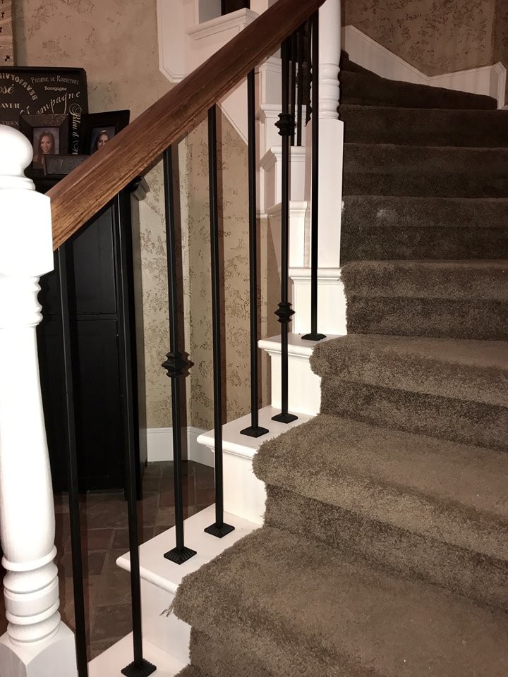 На фото: большая изогнутая лестница в классическом стиле с ступенями с ковровым покрытием, ковровыми подступенками и деревянными перилами