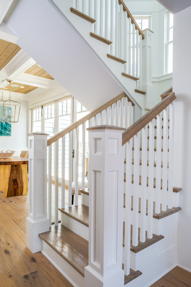 Imagen de escalera en U costera pequeña con escalones de madera, contrahuellas de madera pintada y barandilla de madera