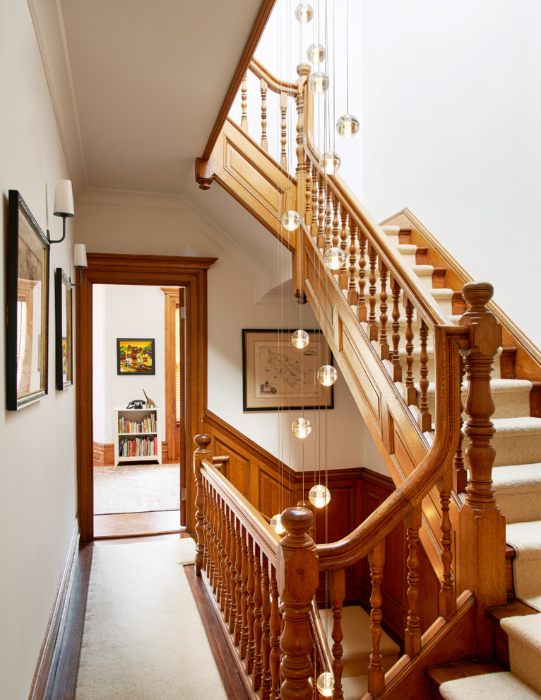 На фото: п-образная лестница в викторианском стиле с ступенями с ковровым покрытием, ковровыми подступенками и деревянными перилами с