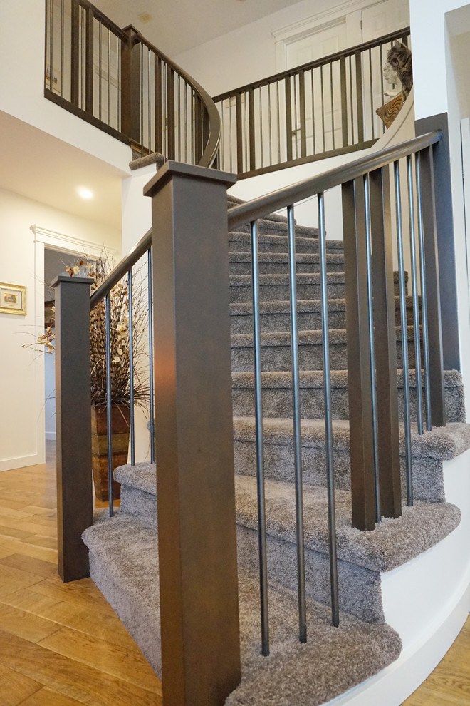 Aménagement d'un grand escalier courbe classique avec des marches en moquette, des contremarches en moquette et un garde-corps en bois.