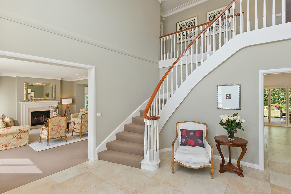 Источник вдохновения для домашнего уюта: большая изогнутая лестница в классическом стиле с ступенями с ковровым покрытием и ковровыми подступенками