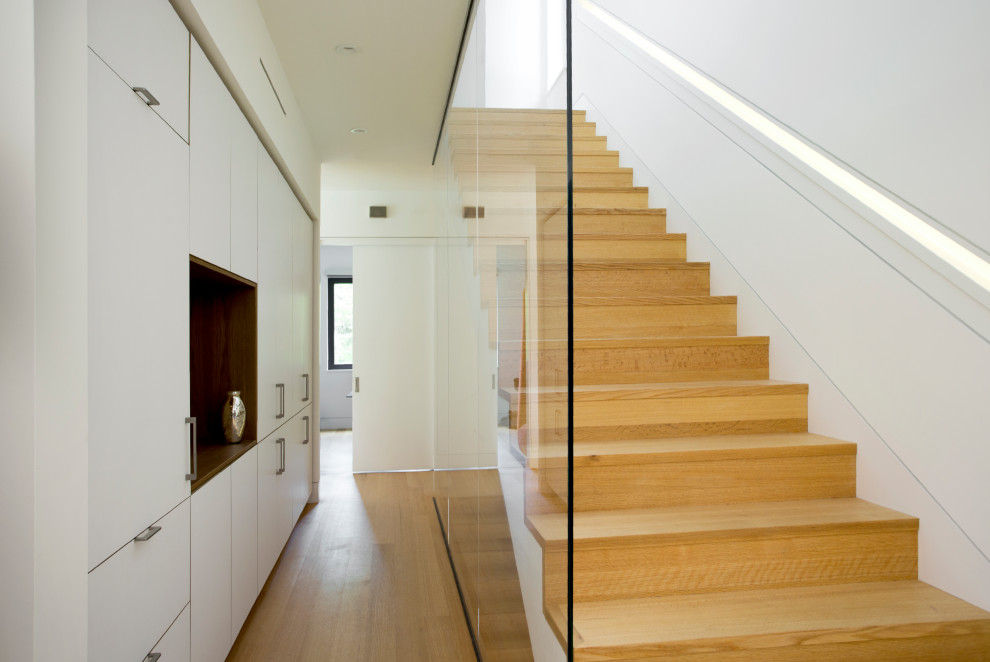 Идея дизайна: прямая лестница в стиле модернизм с деревянными ступенями и стеклянными подступенками
