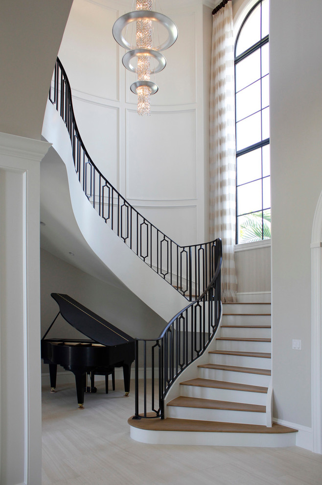 Источник вдохновения для домашнего уюта: большая изогнутая лестница в классическом стиле с деревянными ступенями и крашенными деревянными подступенками