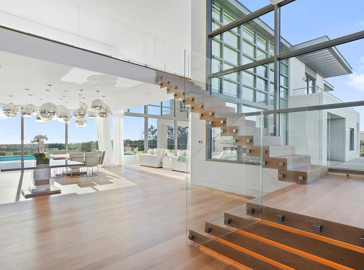 Пример оригинального дизайна: большая угловая деревянная лестница в современном стиле с деревянными ступенями и стеклянными перилами