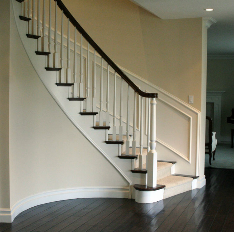 Imagen de escalera curva tradicional con escalones de madera, contrahuellas de madera pintada, barandilla de madera y madera