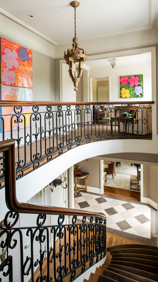 Идея дизайна: большая изогнутая лестница в классическом стиле с деревянными ступенями и крашенными деревянными подступенками