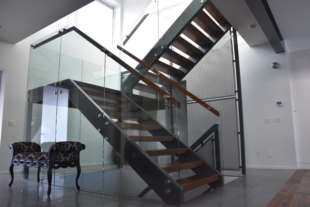 Diseño de escalera en U minimalista grande sin contrahuella con escalones de madera y barandilla de vidrio