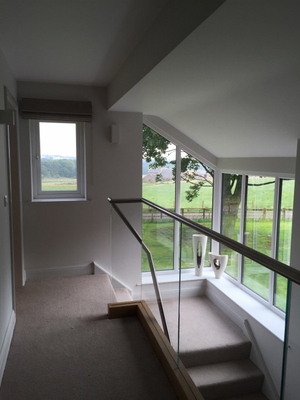 Photo of a medium sized contemporary carpeted l-shaped glass railing staircase in Other with carpeted risers.