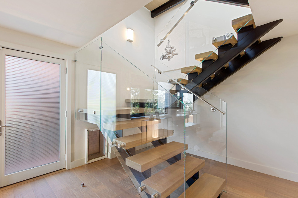 Imagen de escalera suspendida minimalista grande sin contrahuella con escalones de madera y barandilla de vidrio