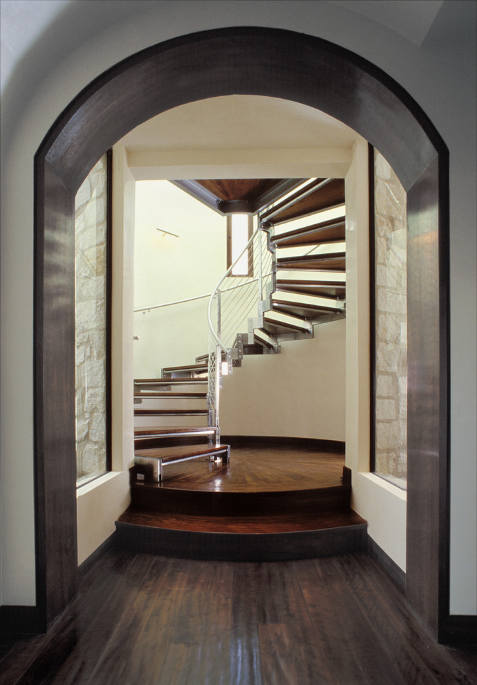 На фото: большая винтовая лестница в средиземноморском стиле с деревянными ступенями и металлическими перилами без подступенок с