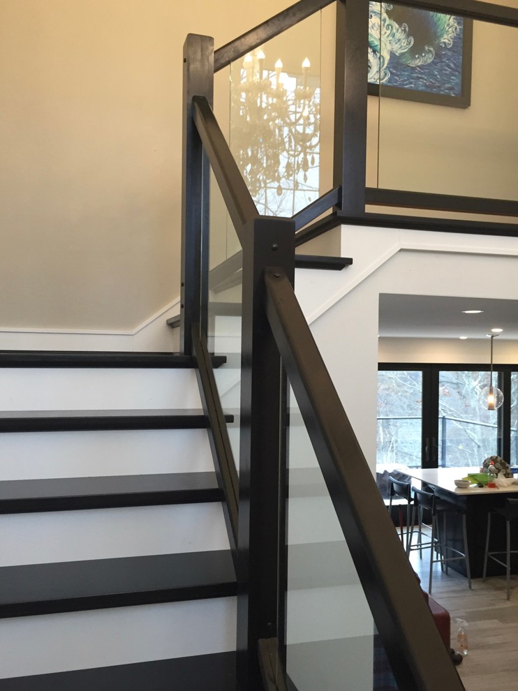 Idée de décoration pour un escalier peint design en L de taille moyenne avec des marches en bois et un garde-corps en verre.