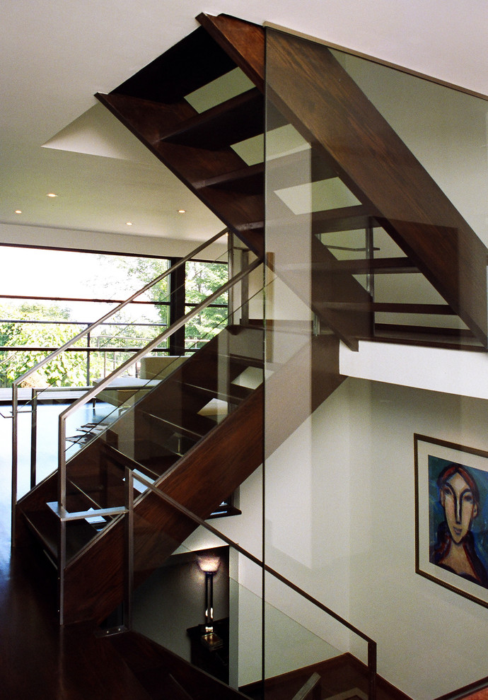 Imagen de escalera minimalista sin contrahuella con escalones de madera y barandilla de vidrio