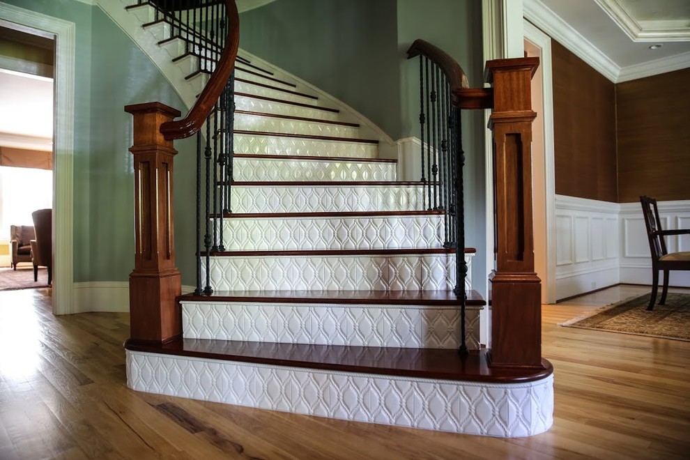 Cette image montre un grand escalier courbe traditionnel avec des marches en bois et des contremarches carrelées.