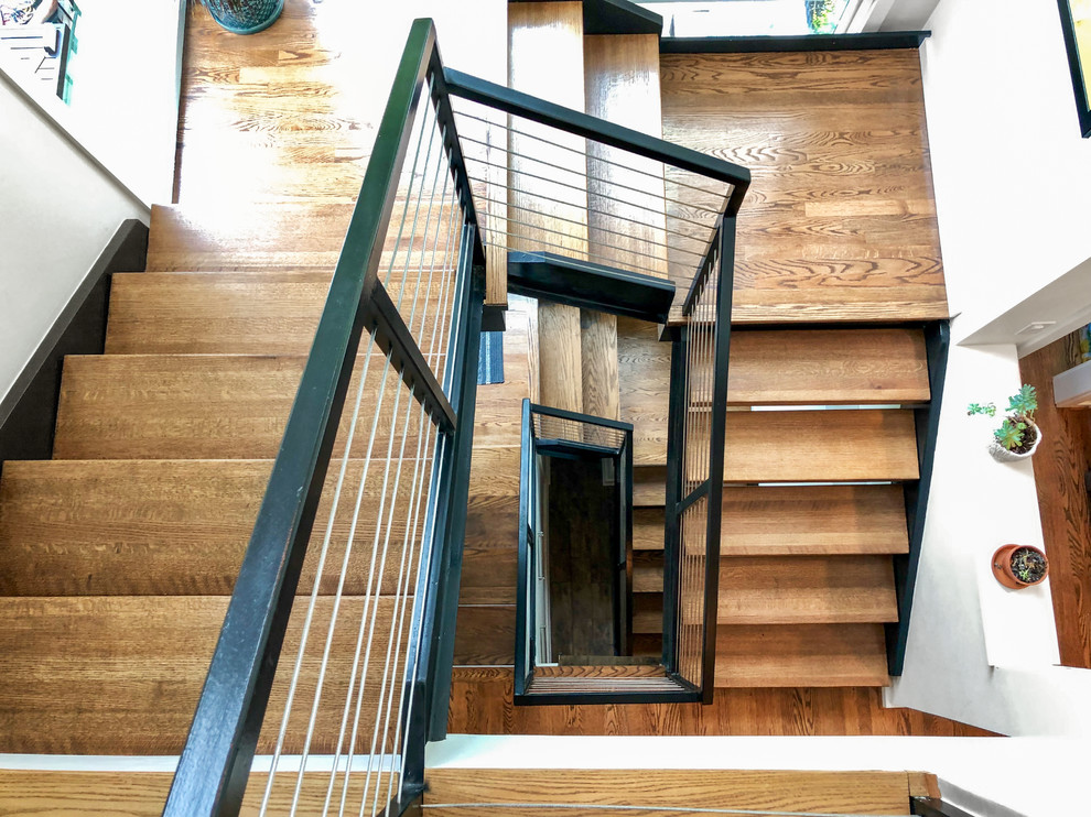 Exemple d'un grand escalier sans contremarche hélicoïdal chic avec des marches en bois et un garde-corps en métal.