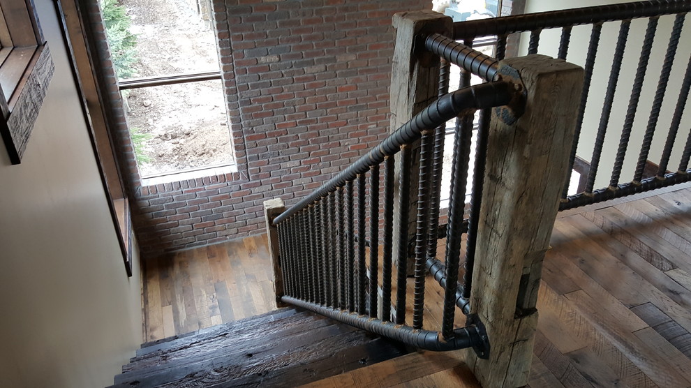 他の地域にある広いインダストリアルスタイルのおしゃれなかね折れ階段 (木の蹴込み板、金属の手すり) の写真