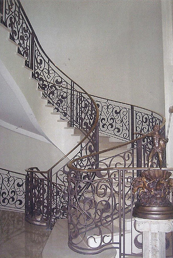 Large traditional concrete curved metal railing staircase in San Diego with painted wood risers.