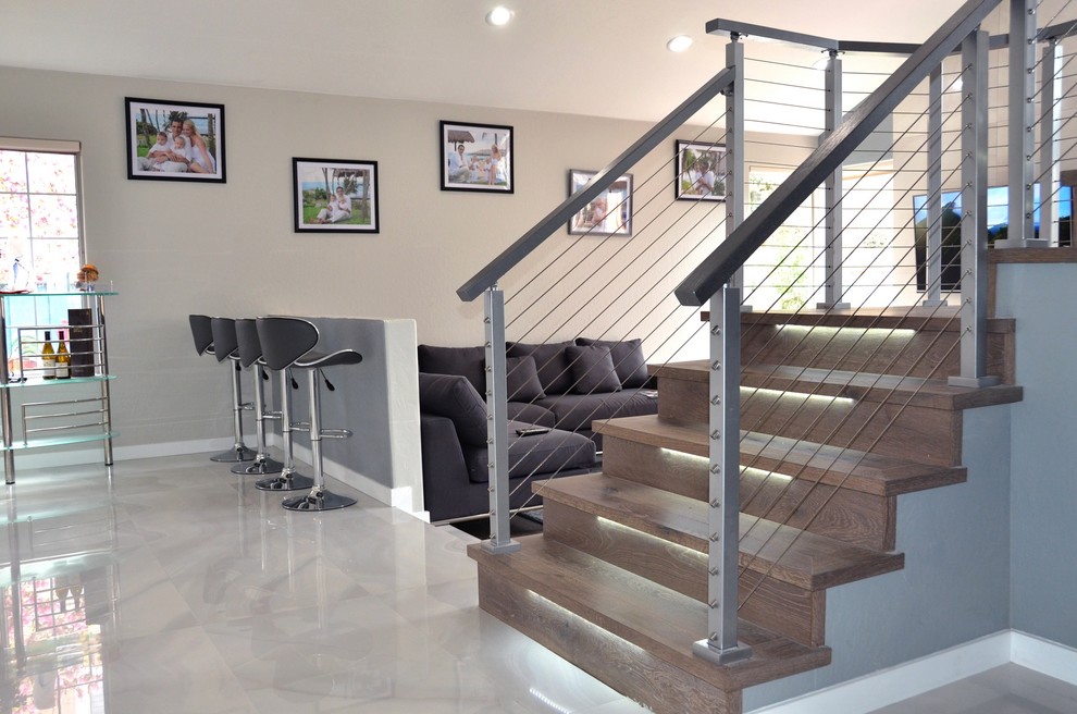 Cette image montre un escalier design en U de taille moyenne avec des marches en bois, des contremarches en bois et un garde-corps en métal.