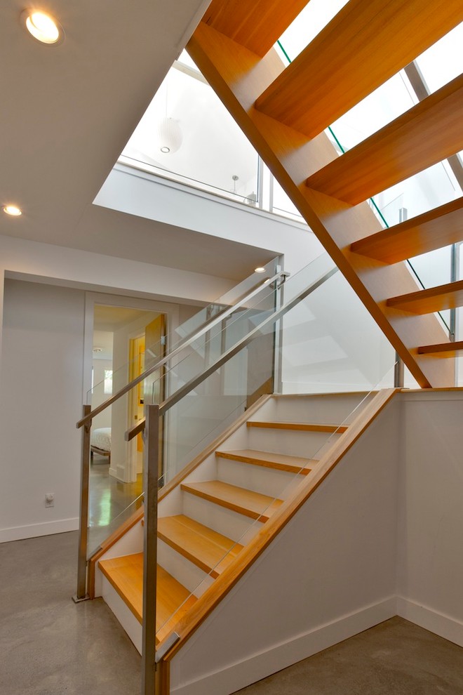 This is an example of a modern staircase in Calgary with open risers and feature lighting.