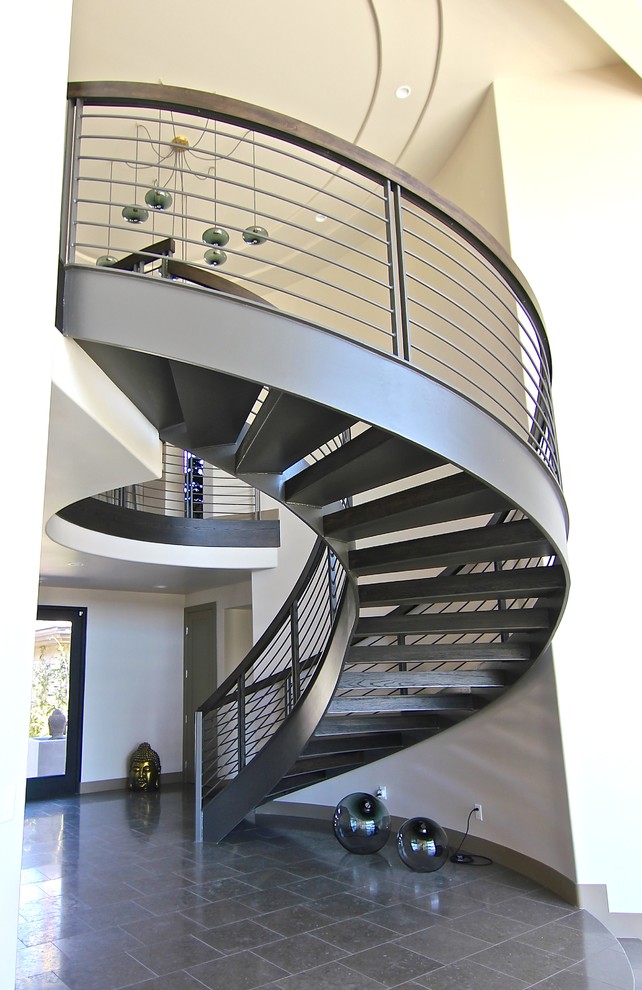 На фото: огромная изогнутая лестница в стиле модернизм с крашенными деревянными ступенями без подступенок