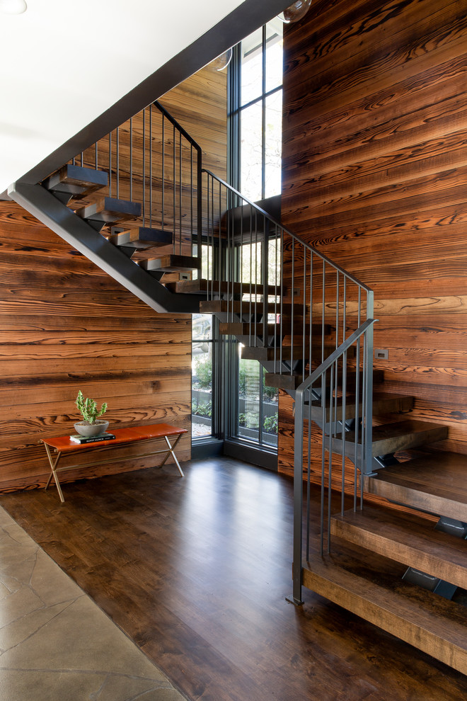 Idée de décoration pour un grand escalier sans contremarche design en U avec des marches en bois et un garde-corps en métal.