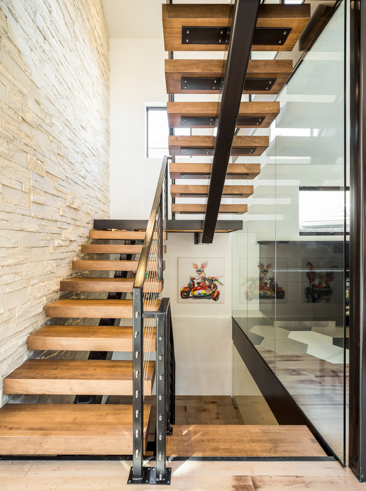 Cette photo montre un grand escalier sans contremarche tendance en U avec des marches en bois et un garde-corps en câble.