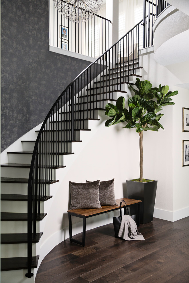 Modelo de escalera curva tradicional renovada grande con barandilla de metal, escalones de madera y contrahuellas de madera pintada