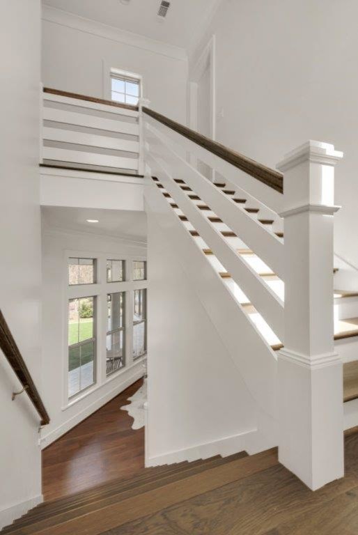 Diseño de escalera en U de estilo de casa de campo grande con escalones de madera, contrahuellas de madera pintada y barandilla de madera