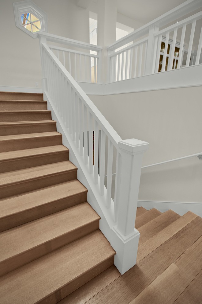 Diseño de escalera en U actual grande con escalones de madera, contrahuellas de madera y barandilla de madera