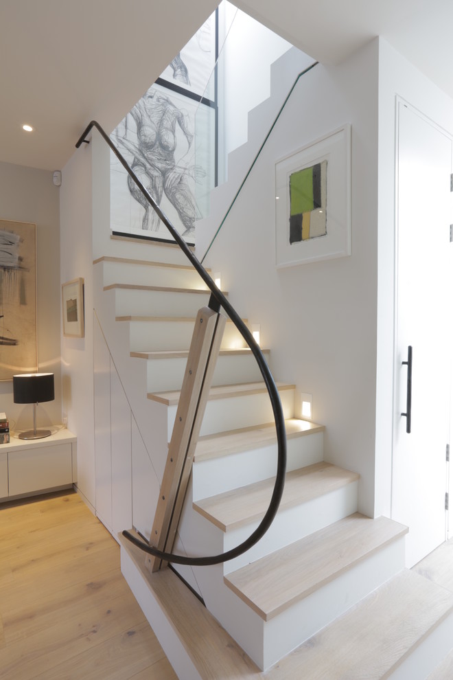 Medium sized contemporary wood u-shaped metal railing staircase in London with painted wood risers and feature lighting.