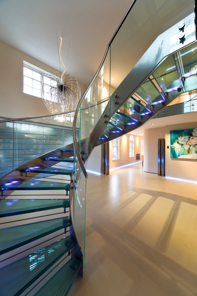 Источник вдохновения для домашнего уюта: большая винтовая лестница в современном стиле с стеклянными ступенями, стеклянными подступенками и металлическими перилами