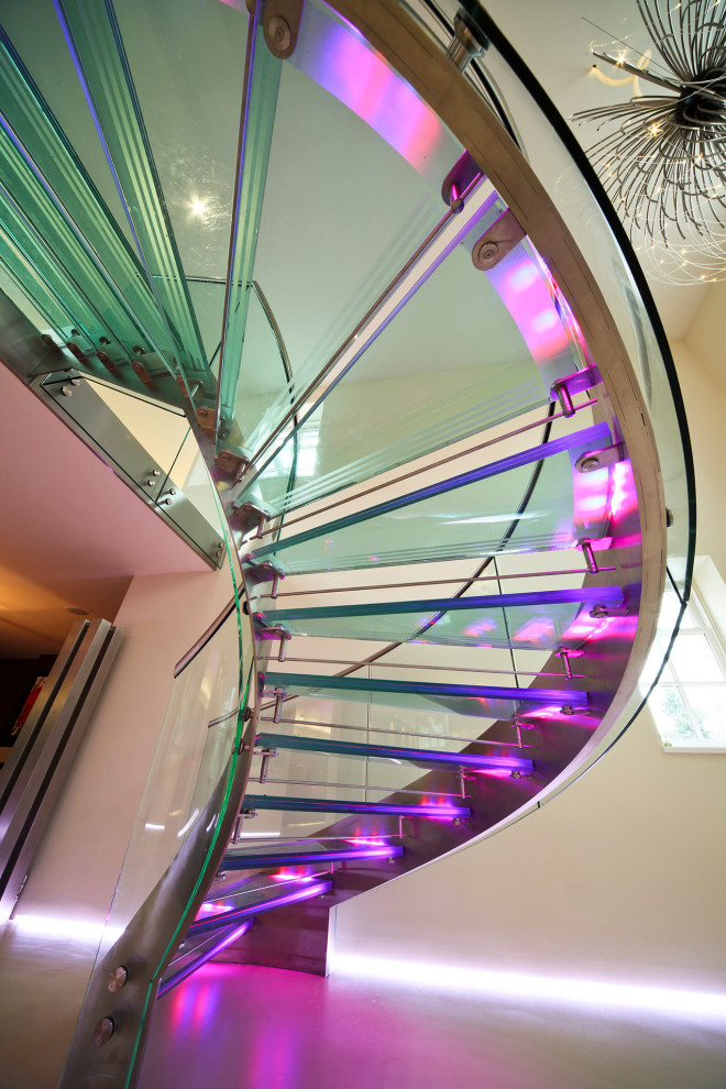 Идея дизайна: большая винтовая лестница в современном стиле с стеклянными ступенями, стеклянными подступенками и металлическими перилами