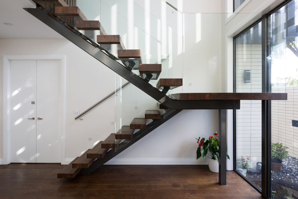 Large modern wood floating glass railing staircase in Auckland with open risers.