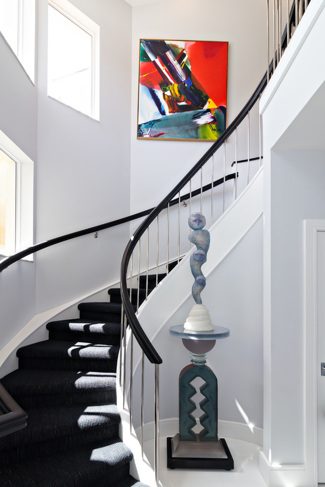 Стильный дизайн: изогнутая лестница в современном стиле с ступенями с ковровым покрытием и ковровыми подступенками - последний тренд