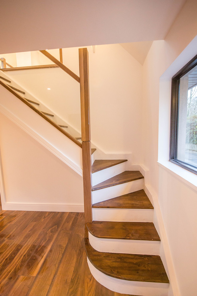 Imagen de escalera en L actual con escalones de madera y barandilla de vidrio