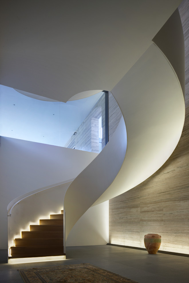 На фото: большая изогнутая лестница в стиле модернизм
