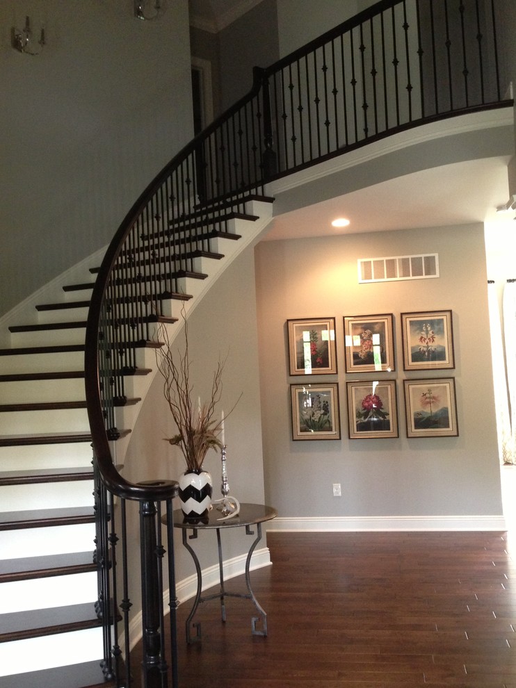 Design ideas for a large classic wood curved wood railing staircase in Columbus with painted wood risers.