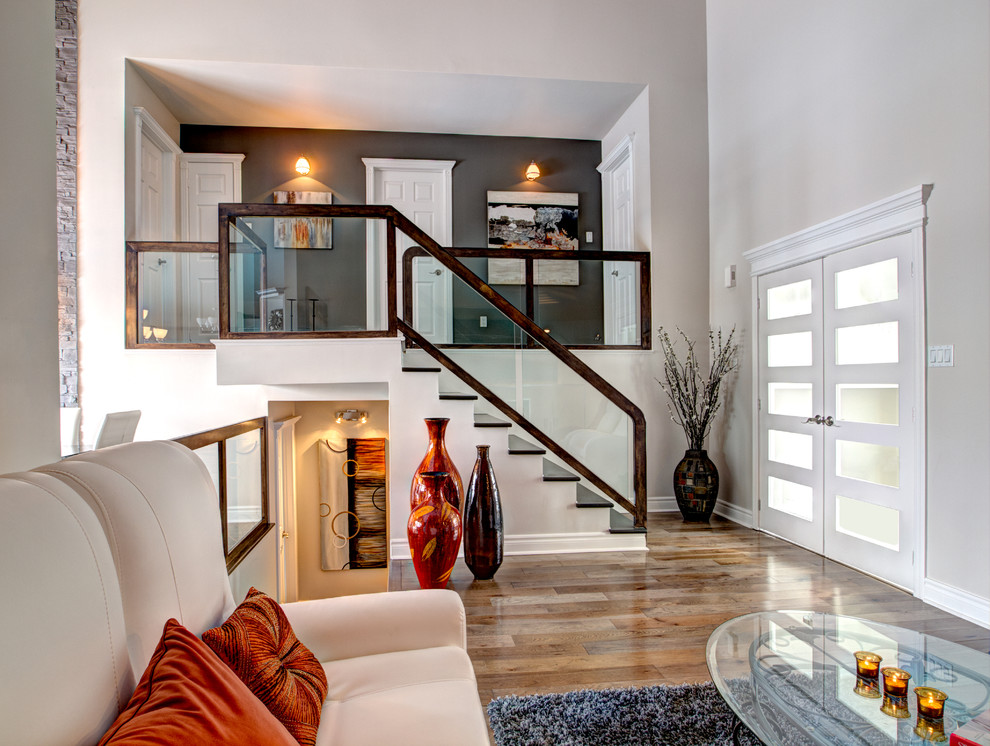 На фото: прямая лестница в стиле неоклассика (современная классика) с деревянными ступенями и стеклянными перилами