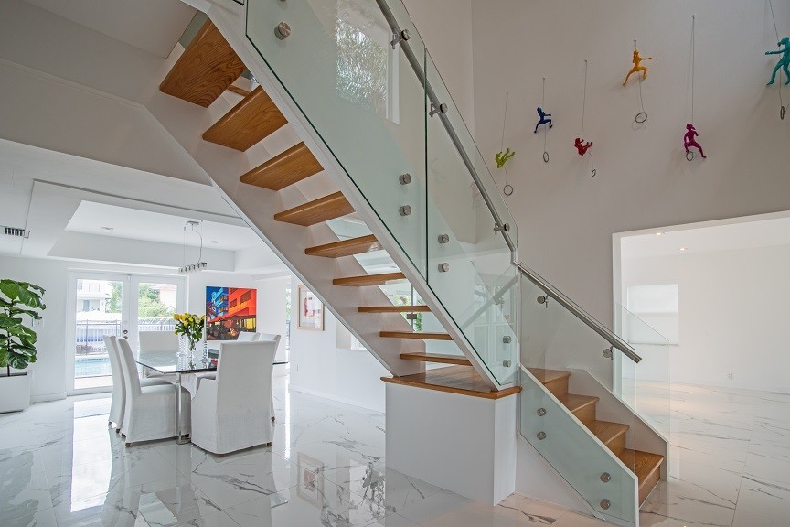 Imagen de escalera en L minimalista de tamaño medio sin contrahuella con escalones de madera y barandilla de vidrio