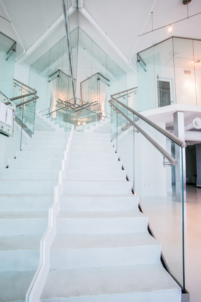 Exemple d'un grand escalier droit moderne en béton avec des contremarches en béton et un garde-corps en verre.