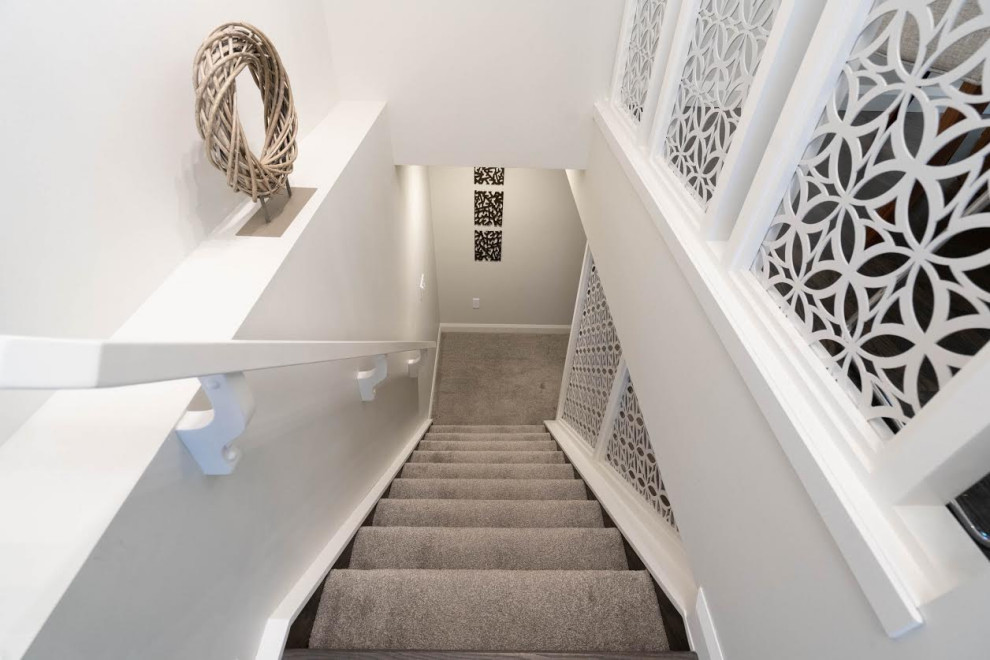 На фото: огромная угловая лестница в стиле ретро с ступенями с ковровым покрытием, ковровыми подступенками и металлическими перилами с
