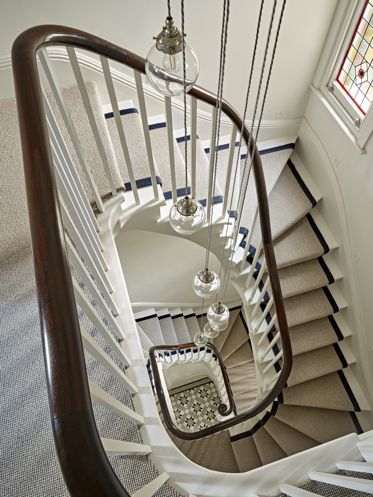 Diseño de escalera curva contemporánea grande con escalones enmoquetados y barandilla de madera