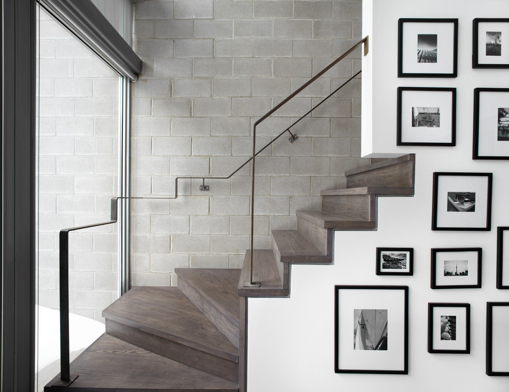 На фото: угловая деревянная лестница в стиле модернизм с деревянными ступенями и металлическими перилами с