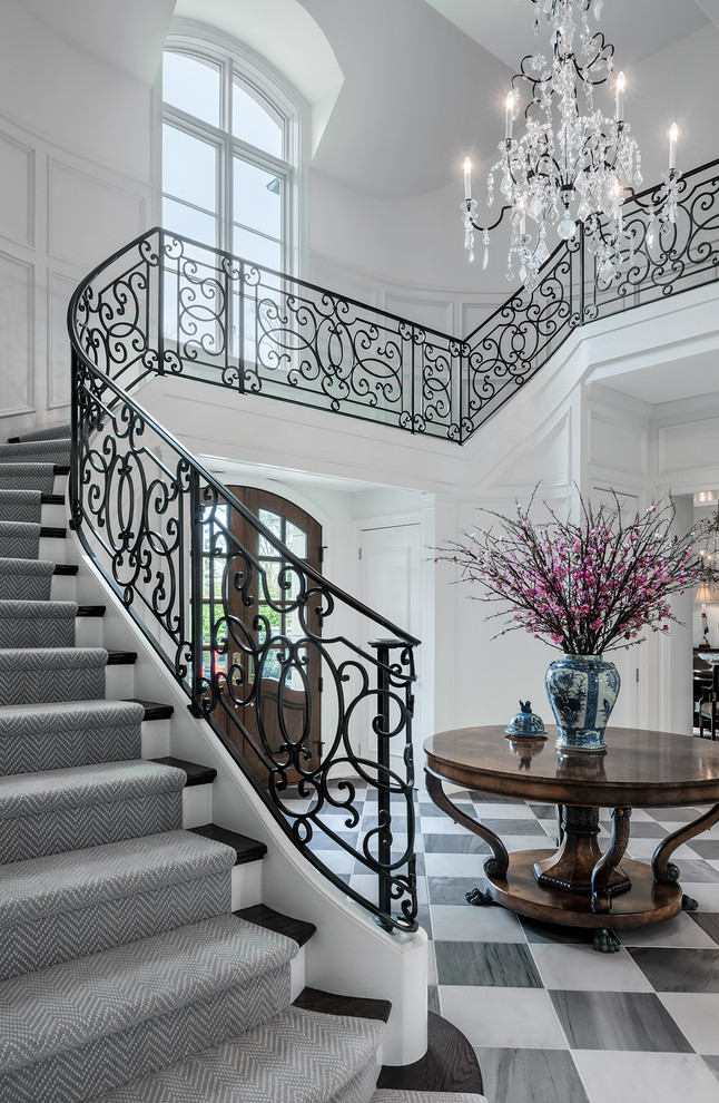 Стильный дизайн: большая изогнутая лестница в классическом стиле с деревянными ступенями и крашенными деревянными подступенками - последний тренд