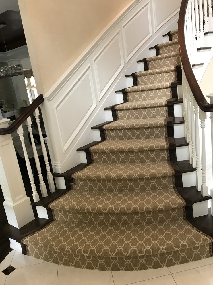 Large classic wood curved wood railing staircase in New York with wood risers.