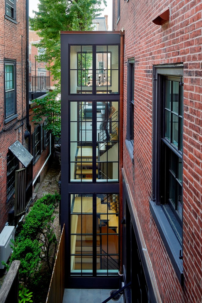 На фото: п-образная металлическая лестница в стиле модернизм с деревянными ступенями и металлическими перилами с