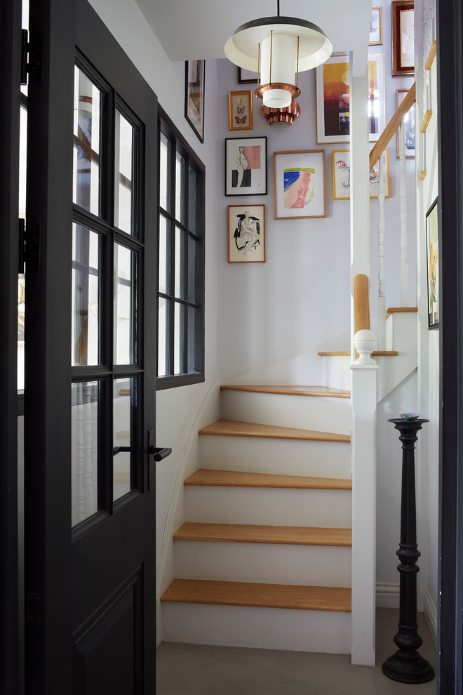 На фото: изогнутая деревянная лестница среднего размера в стиле неоклассика (современная классика) с деревянными ступенями и деревянными перилами
