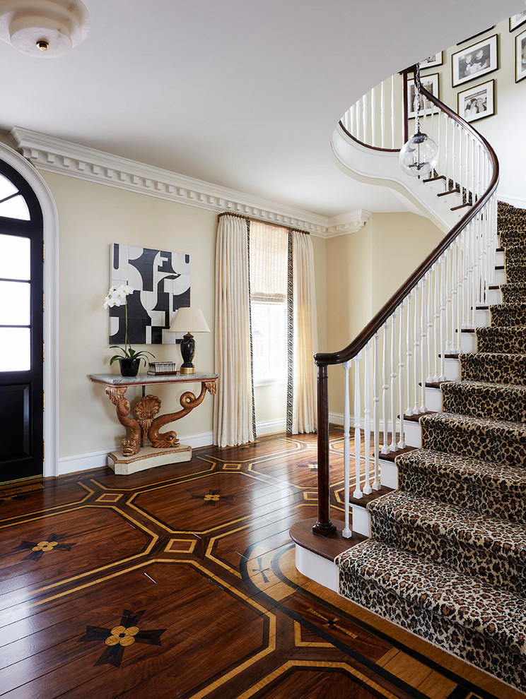 Стильный дизайн: большая изогнутая лестница в классическом стиле с деревянными ступенями и крашенными деревянными подступенками - последний тренд
