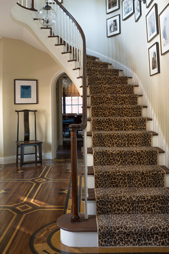 Cette image montre un grand escalier peint courbe traditionnel avec des marches en bois.